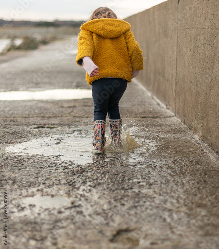 Child splashing in a puddle of rain near the beach