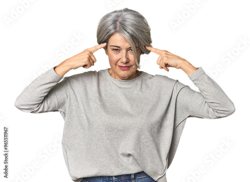 Caucasian mid-age female on studio background focused on a task, keeping forefingers pointing head.