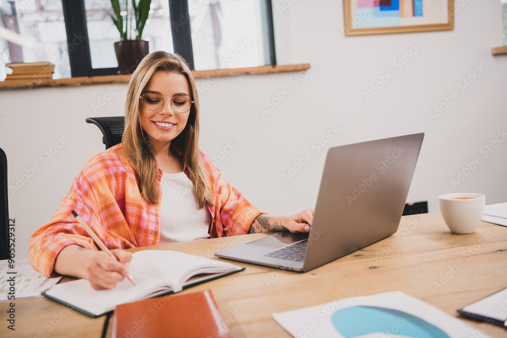 Portrait of pretty young office worker woman laptop write notepad loft interior business center indoors Portrait of pretty young office worker woman laptop write notepad loft interior business center indoors