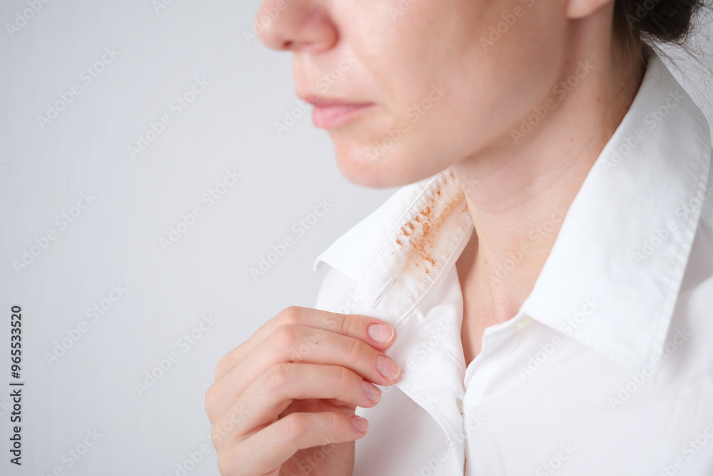 Faceless woman showing a dirty cosmetic stain on the collar of his white shirt in a well-lit room during the day. everyday life stain concept. space for text Faceless woman showing a dirty cosmetic stain on the collar of his white shirt in a well-lit room during the day. everyday life stain concept. space for text