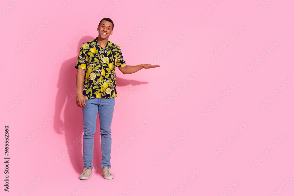 Full length photo of handsome young guy measure empty space dressed stylish tropical print garment isolated on pink color background Full length photo of handsome young guy measure empty space dressed stylish tropical print garment isolated on pink color background