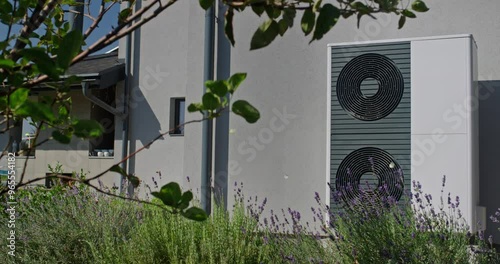 Outdoor heat pump unit with lavender plants in a modern garden setting, with a house in the background. photo