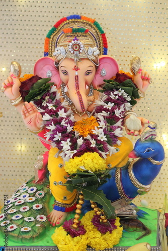 lord ganesha idol on Ganesh chaturthi. little Ganpati is sitting a beautiful peacock in the idol. the temple is decorated with lights and flowers. On the occasion on Ganesh Stapna on chaturthi  photo