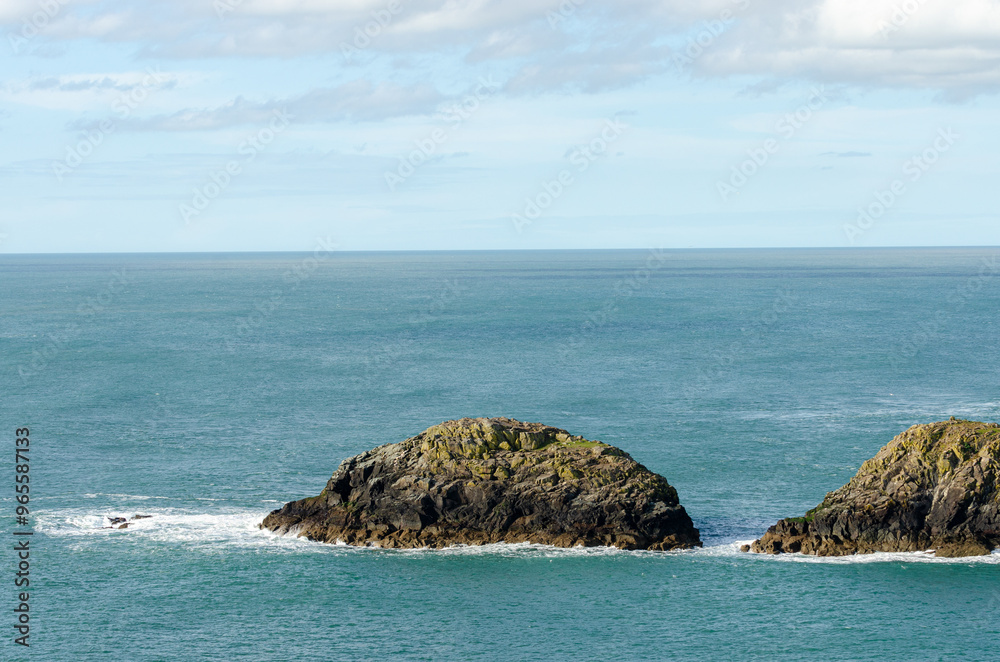 Naklejka premium Small rocky islands in the middle of a calm sea under a bright sky in Wales.