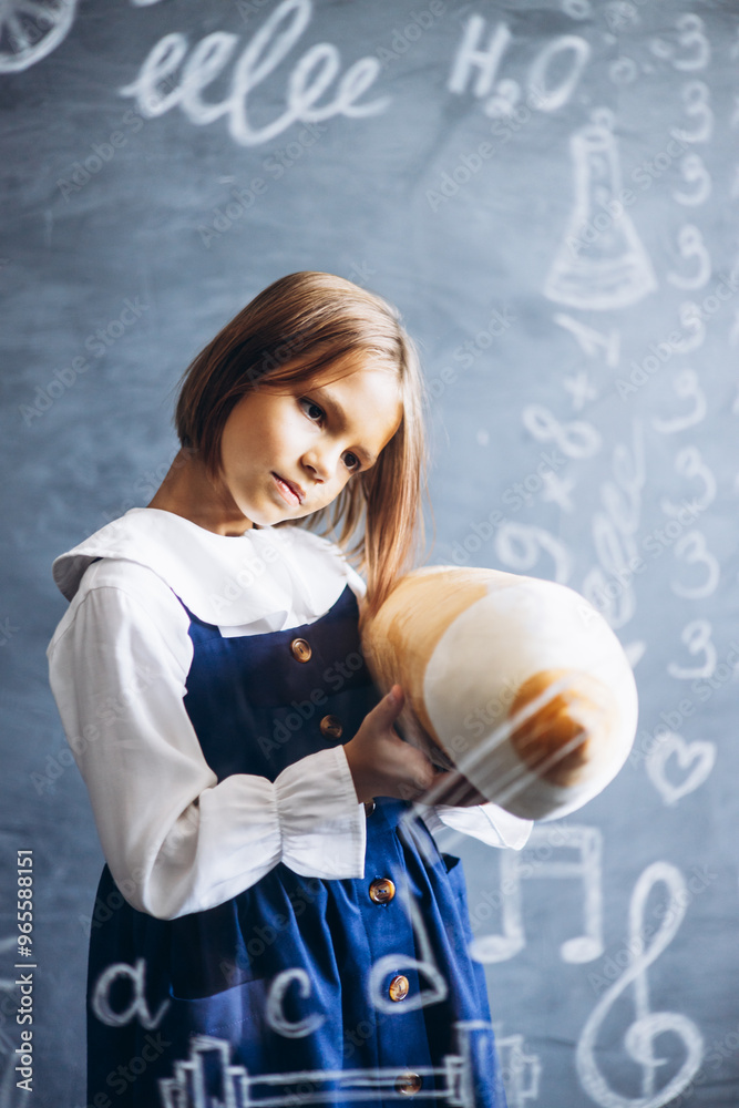Fototapeta premium Cute little schoolgirl standing behind the glass board signed with math formulas