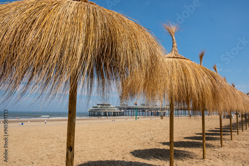 Bild auf Leinwand Eine Reihe mit Bast Sonnenschirmen am Strand von Scheveningen in den Niederlande
