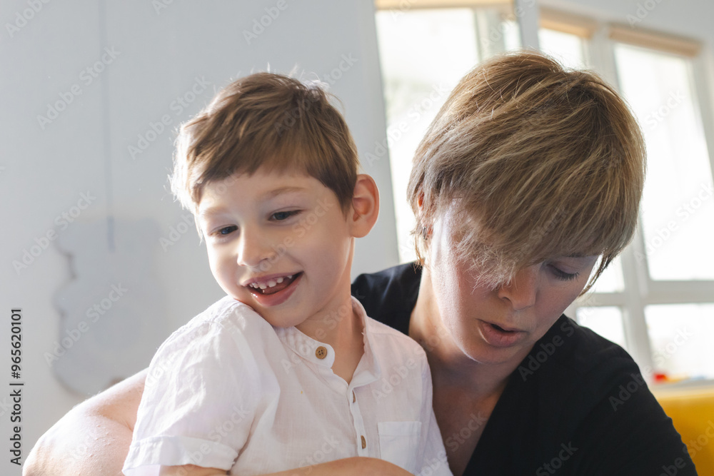Young boy with neurodevelopmental disorders enjoys a physical rehabilitation session with a supportive therapist, smiling during activities Young boy with neurodevelopmental disorders enjoys a physical rehabilitation session with a supportive therapist, smiling during activities