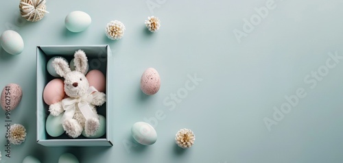 Cute bunny plush toy with pastel eggs on a light blue background, perfect for Easter themes and spring celebrations. photo