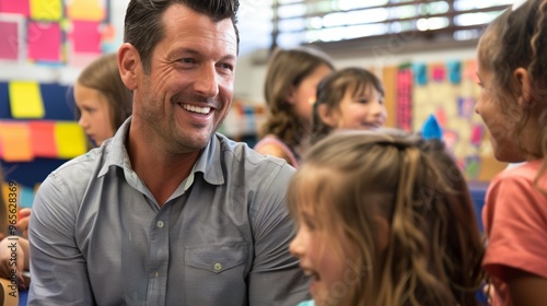 Horizontal portrait of a male teacher smiling while talking to pupils in the classroom
