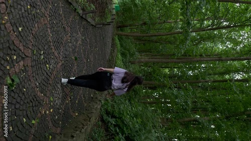 Young woman goes into the distance along the summer alley of the park	 photo