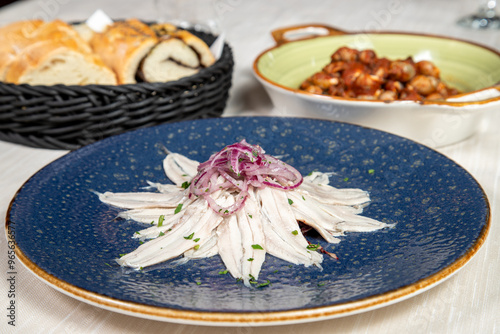 Marinated anchovies served in an elegant dish from a gourmet restaurant.
Pickled anchovies with garlic and parsley marinated in vinegar in a round blue plate