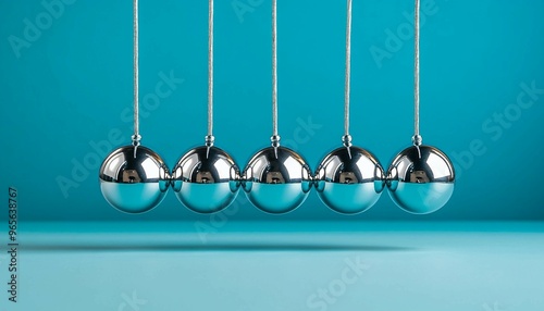 Newton Cradle, silver  balls on a blue background. Physics concept, Motion and energy transfer, Balance and equilibrium.