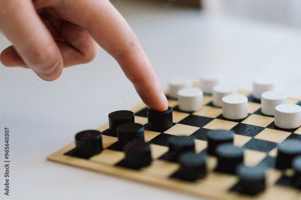 Teenage Girl and Boy Playing Board Game checkers In Living Room. Playing a board game on a white ottoman. They are both focused on the game. Children Playing a Checkerboard Game Indoors Teenage Girl and Boy Playing Board Game checkers In Living Room. Playing a board game on a white ottoman. They are both focused on the game. Children Playing a Checkerboard Game Indoors