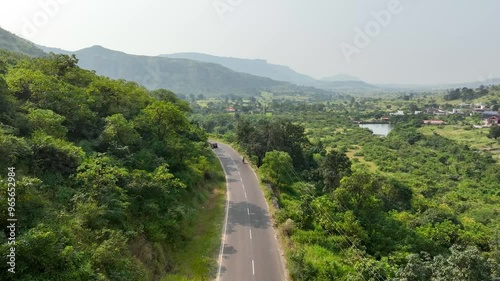 aerial view Car Driving on Country winding Road. vehicle riding fast along mountains. Cinematic drone shot flying over gravel road in forest beautiful nature