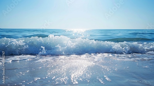 Sunlight reflecting on gentle ocean waves with clear blue sky