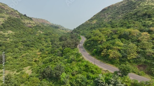 aerial view Car Driving on Country winding Road. vehicle riding fast along mountains. Cinematic drone shot flying over gravel road in forest beautiful nature