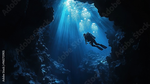 Scuba diver swimming upward in a cavern, illuminated by blue light rays from above