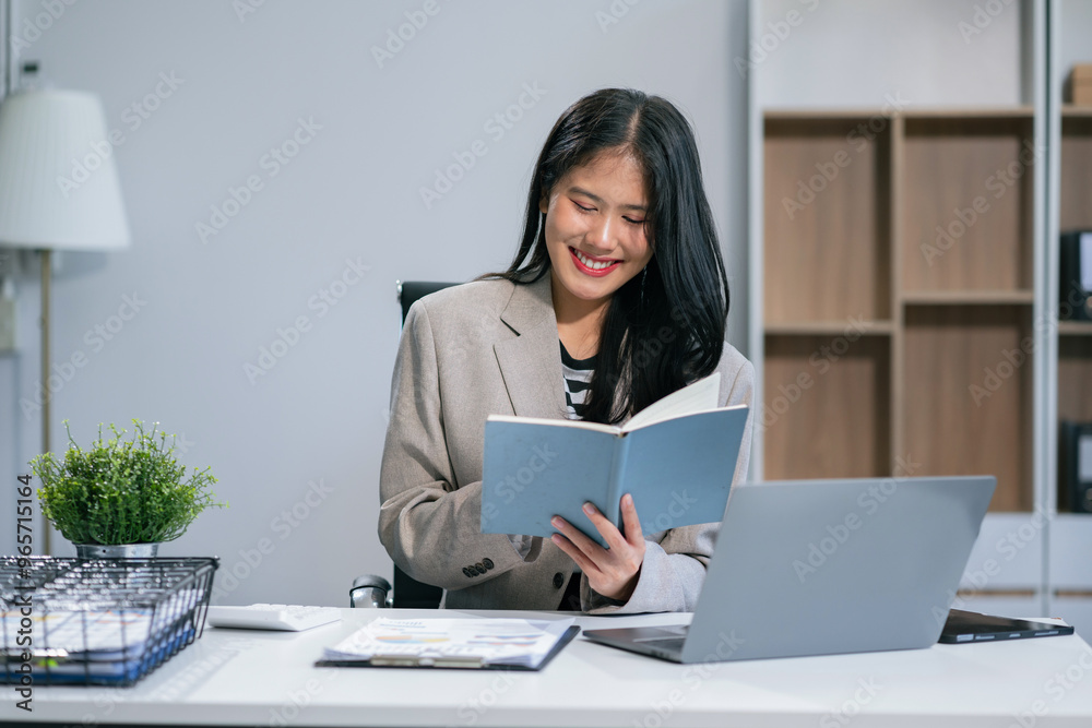 Female hand working search page on computer and writing on a notepad with a pen in the office. on the wooden desk there a graph business diagram. Female hand working search page on computer and writing on a notepad with a pen in the office. on the wooden desk there a graph business diagram.