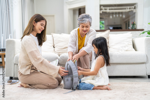 Asian family preparing school backpack together, mother, grandmother and girl child organizing books, back to school concept, family bonding time, education and learning preparation, supportive family