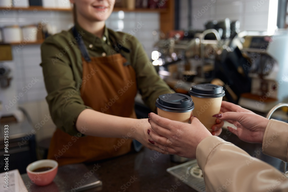 Woman barista serving coffee in takeaway paper cups