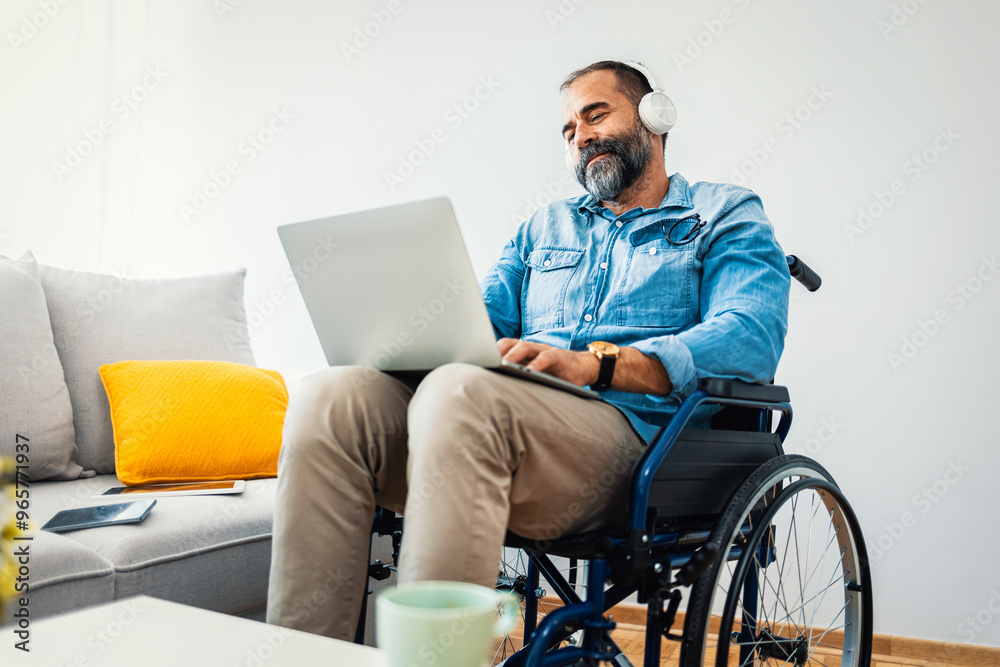 Man in Wheelchair Using Laptop and Headphones at Home Man in Wheelchair Using Laptop and Headphones at Home