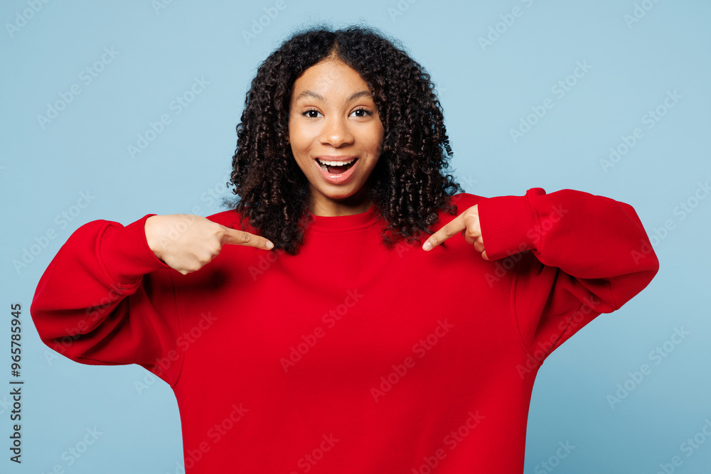 Little shocked surprised kid teen girl of African American ethnicity wear red sweatshirt point index finger on herself isolated on pastel plain light blue cyan background. Childhood lifestyle concept. Little shocked surprised kid teen girl of African American ethnicity wear red sweatshirt point index finger on herself isolated on pastel plain light blue cyan background. Childhood lifestyle concept.