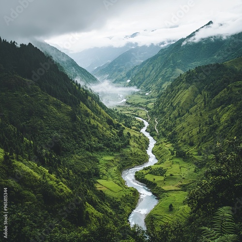 A winding river cuts through a lush green valley, with misty mountains in the background.