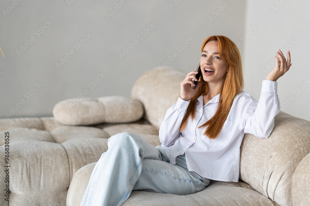 Portrait of a woman using laptop and a phone while sitting on couch at home. Portrait of a woman using laptop and a phone while sitting on couch at home.