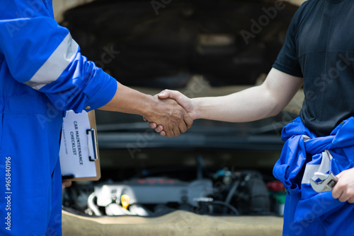 Car service. Mechanic and customer shaking hands. Excellent cooperation between car mechanic and coworker. Close up mechanic and maintenance engineer shaking hands at car workshop.