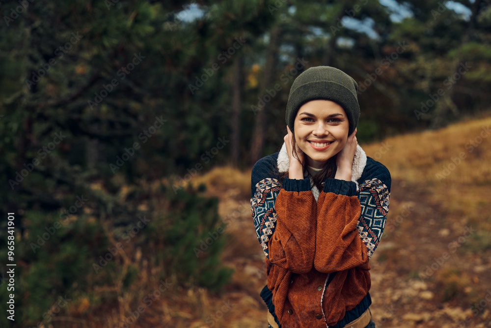 Smiling young woman enjoying autumn beauty in the forest surrounded by colorful leaves and trees Smiling young woman enjoying autumn beauty in the forest surrounded by colorful leaves and trees