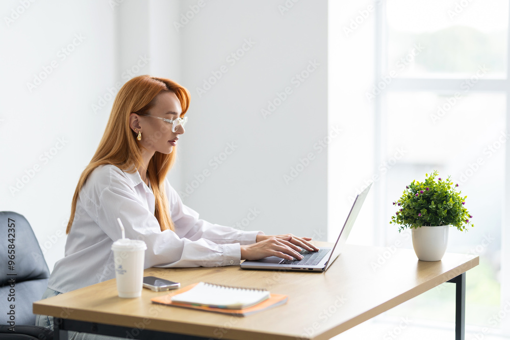 Young beautiful joyful woman smiling while working with laptop in office Young beautiful joyful woman smiling while working with laptop in office