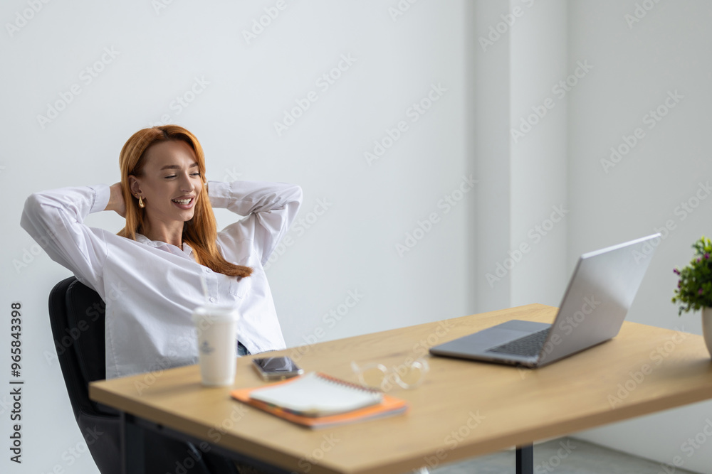 Attractive young woman stretching body and relaxing at the office with legs up on a desk.
