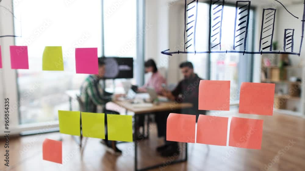 Group of IT experts working on developments in field of artificial intelligence. Brainstorming session with charts and sticky notes on glass wall in modern office environment. Group of IT experts working on developments in field of artificial intelligence. Brainstorming session with charts and sticky notes on glass wall in modern office environment.