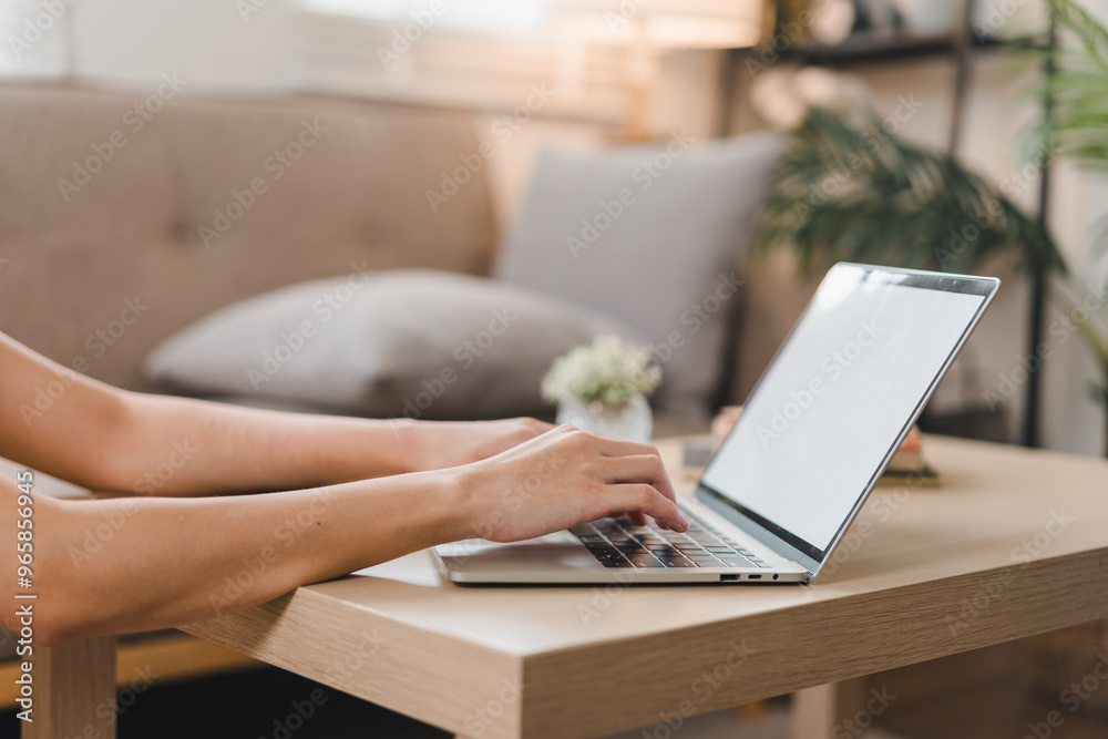A person is working on laptop at cozy home office, surrounded by comfortable sofa and decorative plants, creating productive and inviting atmosphere. A person is working on laptop at cozy home office, surrounded by comfortable sofa and decorative plants, creating productive and inviting atmosphere.
