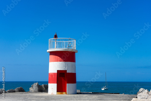 lighthouses on the breakwaters at the entrance of Nazaré Marina, Portugal, standing against the vast Atlantic Ocean under a cloudy sky, marking the way for incoming vessels. photo