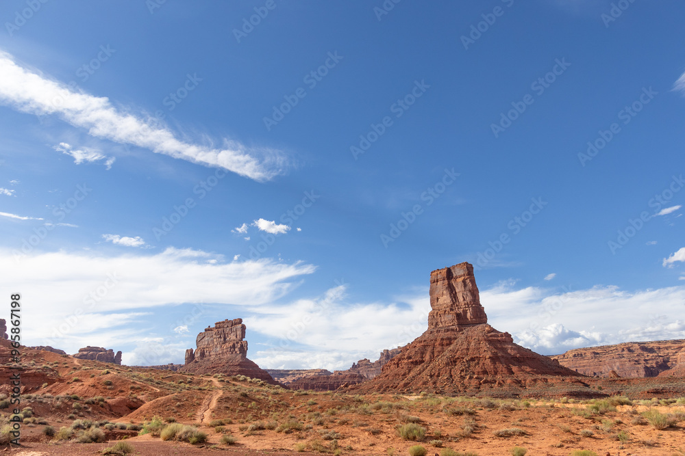 Rock formations in the Valley of the Gods in Utah with red rocks, open desert, and blue skies. Rock formations in the Valley of the Gods in Utah with red rocks, open desert, and blue skies.