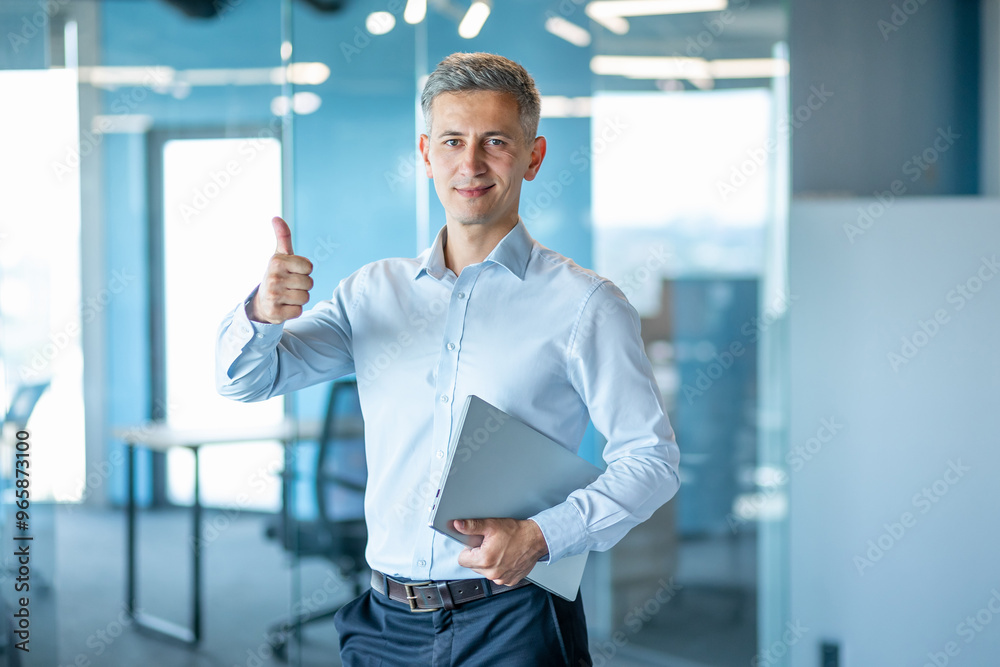 Confident Business Professional Holding Laptop in Office Confident Business Professional Holding Laptop in Office