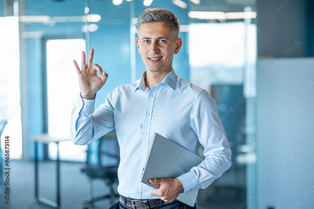 Confident Businessman Gesturing Okay in Modern Office Confident Businessman Gesturing Okay in Modern Office
