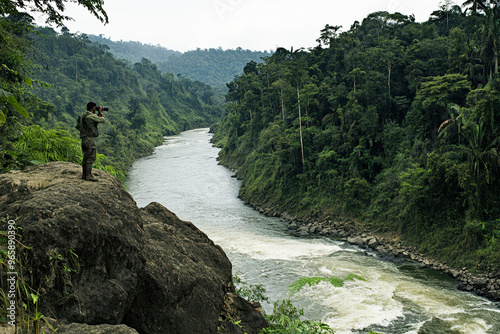 Soldier scanning the jungle from a rocky outcrop overlooking a river.