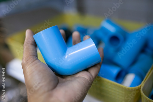 Close up of a hand holding a blue plastic pipe.