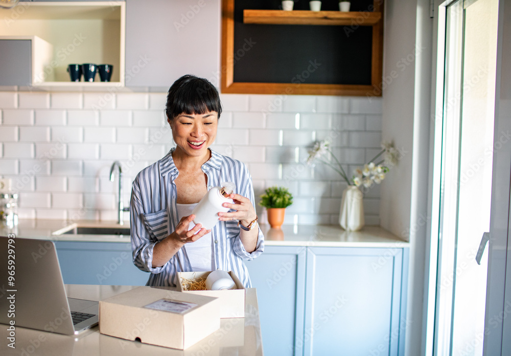 Happy Asian woman opening package in the kitchen Happy Asian woman opening package in the kitchen