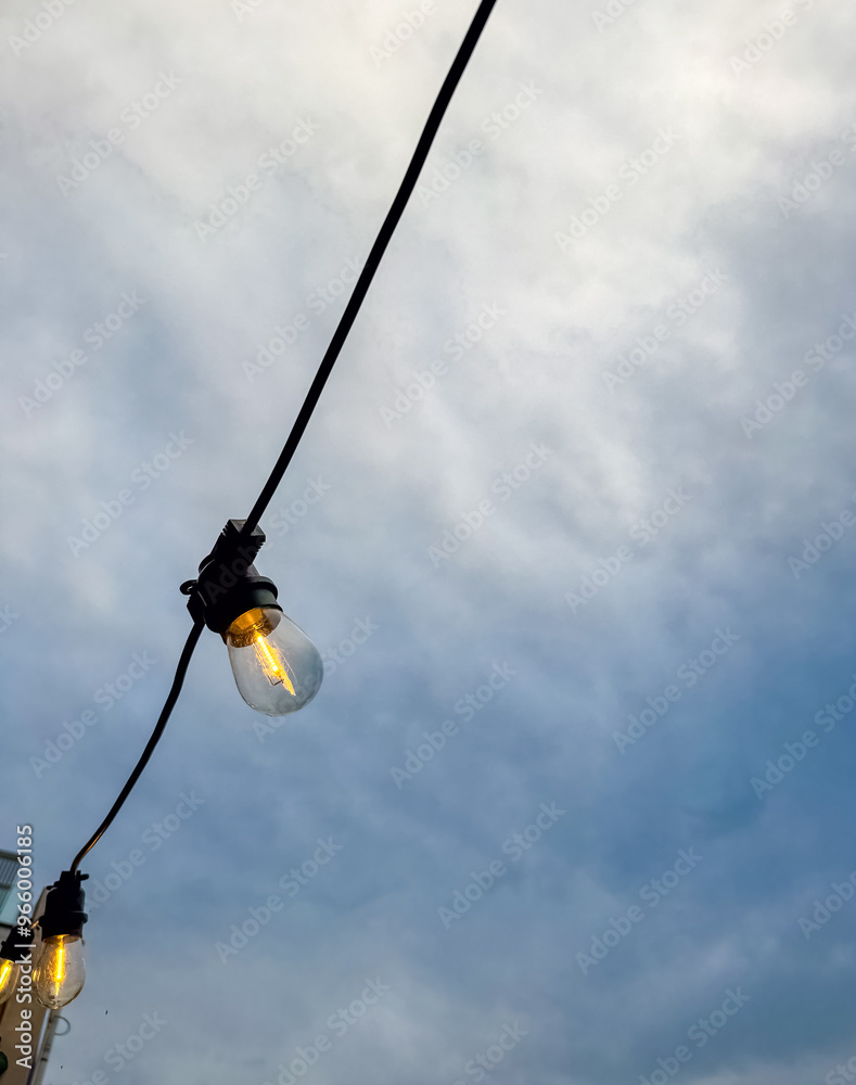 Light bulbs on strings against blue sky with clouds. High quality photo Light bulbs on strings against blue sky with clouds. High quality photo