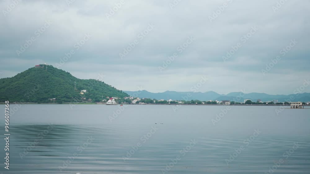 4K shot of Fateh Sagar lake during the monsoon season at Udaipur in Rajasthan, India. Aravalli hills behind the water of the lake with dark stormy clouds in the sky. Natural background with copy space 4K shot of Fateh Sagar lake during the monsoon season at Udaipur in Rajasthan, India. Aravalli hills behind the water of the lake with dark stormy clouds in the sky. Natural background with copy space