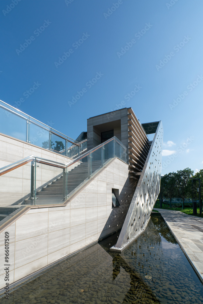 Naklejka premium Modern Architectural Design with Dynamic Stairs and Reflective Water Feature