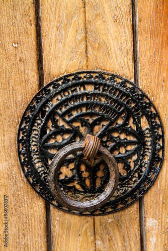 Detailed view of an ornate door knocker on a rustic wooden door in Paris, showcasing intricate design and historical charm