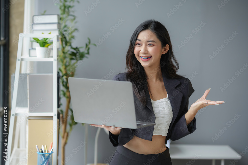Young professional woman holding laptop and gesturing with hand Young professional woman holding laptop and gesturing with hand
