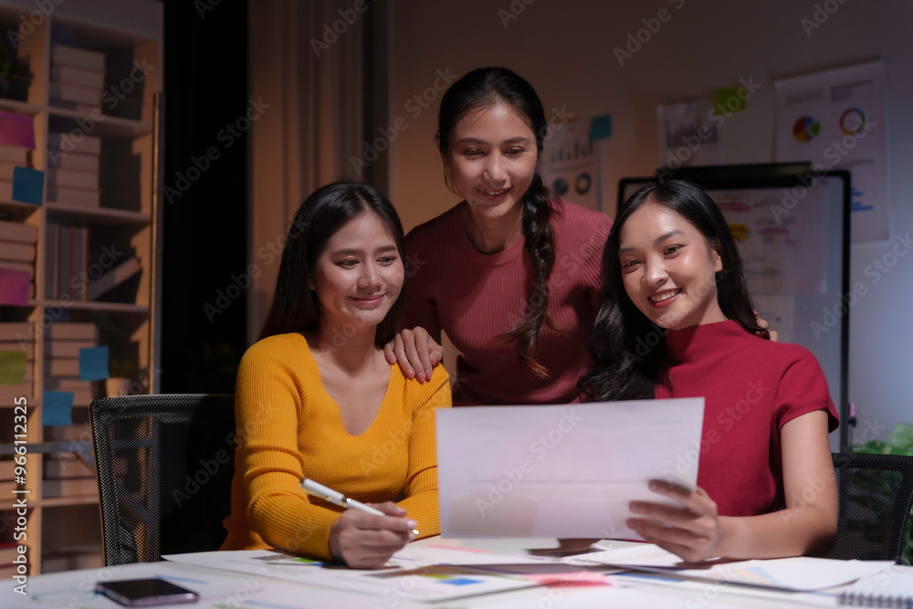 Three asian businesswomen working late and smiling at the office Three asian businesswomen working late and smiling at the office