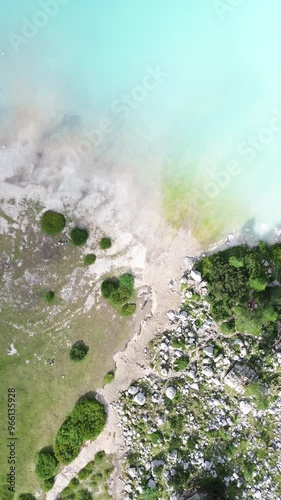 Top shot traveling of a blue mountain lake showing a sandy shore then a forest shore