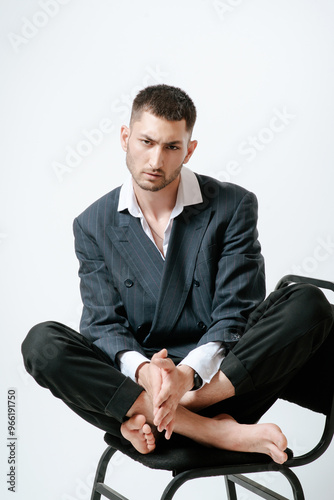 Handsome man, fashion model sits on chair barefoot