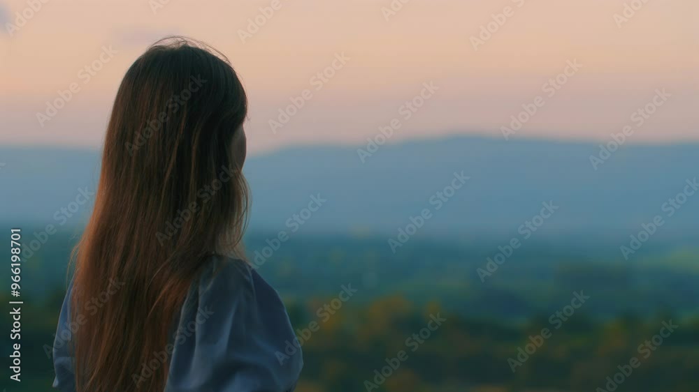 Young woman with long hair gazing at mountainous landscape during sunset with serene and calm atmosphere in background. Young woman with long hair gazing at mountainous landscape during sunset with serene and calm atmosphere in background.